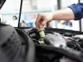 Ręka mechanika dokręca korek zbiorniczka płynu hamulcowego. Czas na badanie techniczne po terminie, by uniknąć problemów.