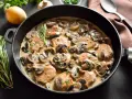 Pyszny schab duszony z pieczarkami w kremowym sosie, udekorowany natką pietruszki i gałązką rozmarynu.