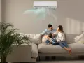 Famiglia felice sul divano, con l'aria condizionata che soffia aria fredda. Scopri come impostare condizionatore aria fredda per un comfort ottimale.