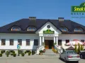 Restauracja "Smak Regionu" z białym budynkiem, schodami i samochodami na parkingu.