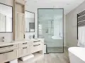Salle de bain moderne avec double vasque en bois clair, douche vitrée et baignoire îlot. Un design épuré pour une ambiance zen.