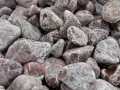 Gładkie, zaokrąglone kamienie o różowych i szarych odcieniach, przypominające porfir.
