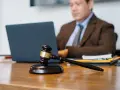 Sądowy młotek na biurku, prawnik pracuje przy laptopie. Dyskrecja w ujawnieniu informacji o zadłużeniu osobom trzecim.