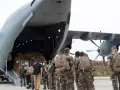 Soldaten mit Rucksäcken stehen vor einem Frachtflugzeug, bereit für ihren Einsatz im Afghanistan-Krieg.