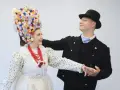 Para tańczy w strojach ludowych, co to folklor. Ona ma bogato zdobiony kwiatami wianek, on czarny kapelusz i marynarkę.