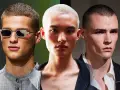 Tre uomini con taglio buzz cut uomo, uno con occhiali scintillanti, uno con capelli biondo platino e uno con sguardo intenso.