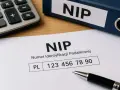 Numer identyfikacji podatkowej, czyli NIP, to ważny dokument. Na zdjęciu widać formularz z numerem NIP, kalkulator i segregator z napisem NIP.