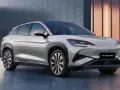 Srebrny SUV BYD Sealion 7 z nowoczesnym designem, zaparkowany przed budynkiem.