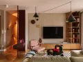 Nowoczesny salon z elementami boho. Wygodna kanapa, różowy fotel, czarne stoliki i regał. W przedpokoju ławka i lustro. Idealne miejsce na relaks po całym dniu. Ten **kosztorys remontu** był wart każdej złotówki.