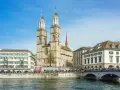 Zurych co warto zobaczyć: imponująca katedra Grossmünster z dwiema wieżami, rzeka Limmat i most.