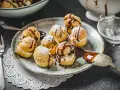 Köstliche Profiteroles, bestäubt mit Puderzucker und beträufelt mit Schokoladensauce. Ein wahrer Genuss, wie beim original profiteroles rezept.