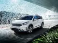 Biały Kia Niro Plug-in Hybrid na drewnianej platformie, otoczony wodnymi kaskadami i zielenią.