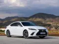 Biały Lexus ES 300h zaparkowany na tle górskiego krajobrazu. Elegancki sedan prezentuje się okazale na tle natury.