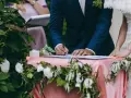 Pan młody podpisuje dokumenty, a obok stoi panna młoda. Zastanawiasz się, ile kosztuje ślub cywilny?