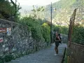 Una ragazza con zaino su un sentiero panoramico, con un cartello che indica Camogli. Perfetto per chi cerca dove dormire sul Cammino del Tigullio.