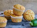 Saftige zucchini-muffins auf einem Gitter, daneben eine frische Zucchini.