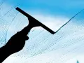 Silueta de mano limpiando ventana con rasqueta, dejando un rastro de burbujas. Un método sencillo para saber como limpiar piedra y superficies.