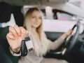 Kobieta w samochodzie trzyma kluczyki do auta.