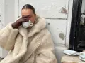Vanilla girl w kremowym futrze pije kawę, otulona ciepłem i spokojem.