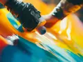 Hands in black gloves apply vibrant acrylic paint to a glossy surface, demonstrating how to paint acrylic plastic with a fluid art technique.