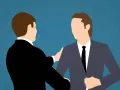 Deux hommes en costume se serrent la main, symbolisant un accord mutuel pour comment négocier une rupture conventionnelle.