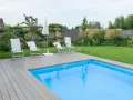 Basen w ogrodzie z leżakami i parasolem. Zastanawiasz się, ile kosztuje zrobienie basenu w ogrodzie?