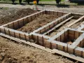 Zbrojenie ławy fundamentowej 40x60 w drewnianym szalunku, gotowe do zalania betonem.