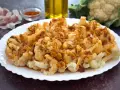 Coliflor al ajillo servida en un plato blanco, con ajo laminado y pimentón espolvoreado.