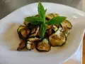 Zucchine alla scapece dorate e croccanti, guarnite con foglie di menta fresca, servite su un piatto bianco.