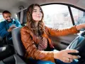 Fahrerin im Taxi, ihr Fahrgast schaut aufs Handy. Sie hat ihren Taxi Schein gut sichtbar.