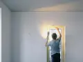 Mężczyzna maluje białe ściany i drzwi z ościeżnicą regulowaną.