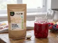 Pektyna do dżemów, cytrusowo-jabłkowa, to naturalny zagęstnik. Na stole słoik z malinowym dżemem, owoce i opakowanie produktu.