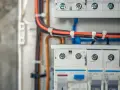 Wnętrze puszki elektrycznej z przewodami i wyłącznikami.