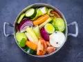 Olla con verduras cortadas en trozos: cebolla, zanahoria, calabacín, puerro, tomate y ajo.