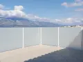 En balkong med insynsskydd av ribbor, som ger avskildhet mot en vacker vy av berg och hav under en molnig himmel.