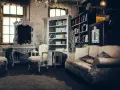 Salotto con divano, poltrone, specchio barocco e librerie. Un esempio di arredamento massimalista che unisce elementi classici e decorazioni elaborate.