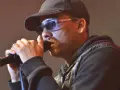 Mann mit Kappe und Sonnenbrille singt ins Mikrofon. Ein starker musik comeback Moment.
