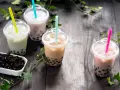 Różne rodzaje herbaty do bubble tea: zielona, mleczna, brązowa i różowa, z tapioką.