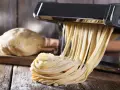 Maszyna do makaronu tworzy świeże tagliatelle z ciasta. Idealny sposób, jak zrobić makaron w domu.