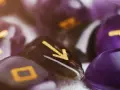 Kamienie z runami, w tym symbol przypominający numerologiczną 1, tworzą mistyczną kompozycję.