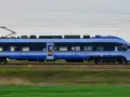Pociąg PKP Intercity w ruchu, z widocznymi oknami i logo przewoźnika.