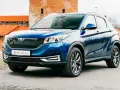Błękitny SUV EV Motors.eu z charakterystycznym grillem, zaparkowany przed zabytkowym budynkiem z cegły.