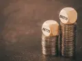 Dwie wieże monet, jedna z napisem "NETTO", druga z "BRUTTO". Symbolizują różnicę między zarobkami, pokazując, jak średnia krajowa netto różni się od brutto.