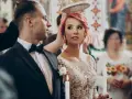 Para ślubna w kościele, z koroną nad głowami. Panna młoda w koronkowej sukni, pan młody w garniturze. W tle goście. Zastanawiasz się, jakie dokumenty do ślubu?