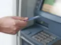 Dłoń z kartą zbliża się do bankomatu. Może to być związane z obsługą konta w Credit Agricole, a nie z zajęciami komorniczymi.