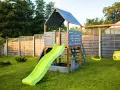 Drewniany domek ze zjeżdżalnią i huśtawkami. Idealne miejsce do zabawy, jak zrobić schody do domku dla dzieci?
