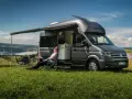 Mężczyzna odpoczywa przy kamperze VW California. Wymiary tego pojazdu pozwalają na komfortowe podróżowanie i biwakowanie.