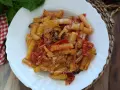 Piatto di pasta con zucchine e pomodorini, condita con formaggio grattugiato e basilico fresco.