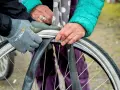 Två personer byter cykelslang. En med grå handske och en med grön jacka och prickig scarf.