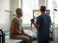 Lekarz wyjaśnia pacjentowi, jak przygotować się do kolonoskopii, pokazując obraz z endoskopu.
